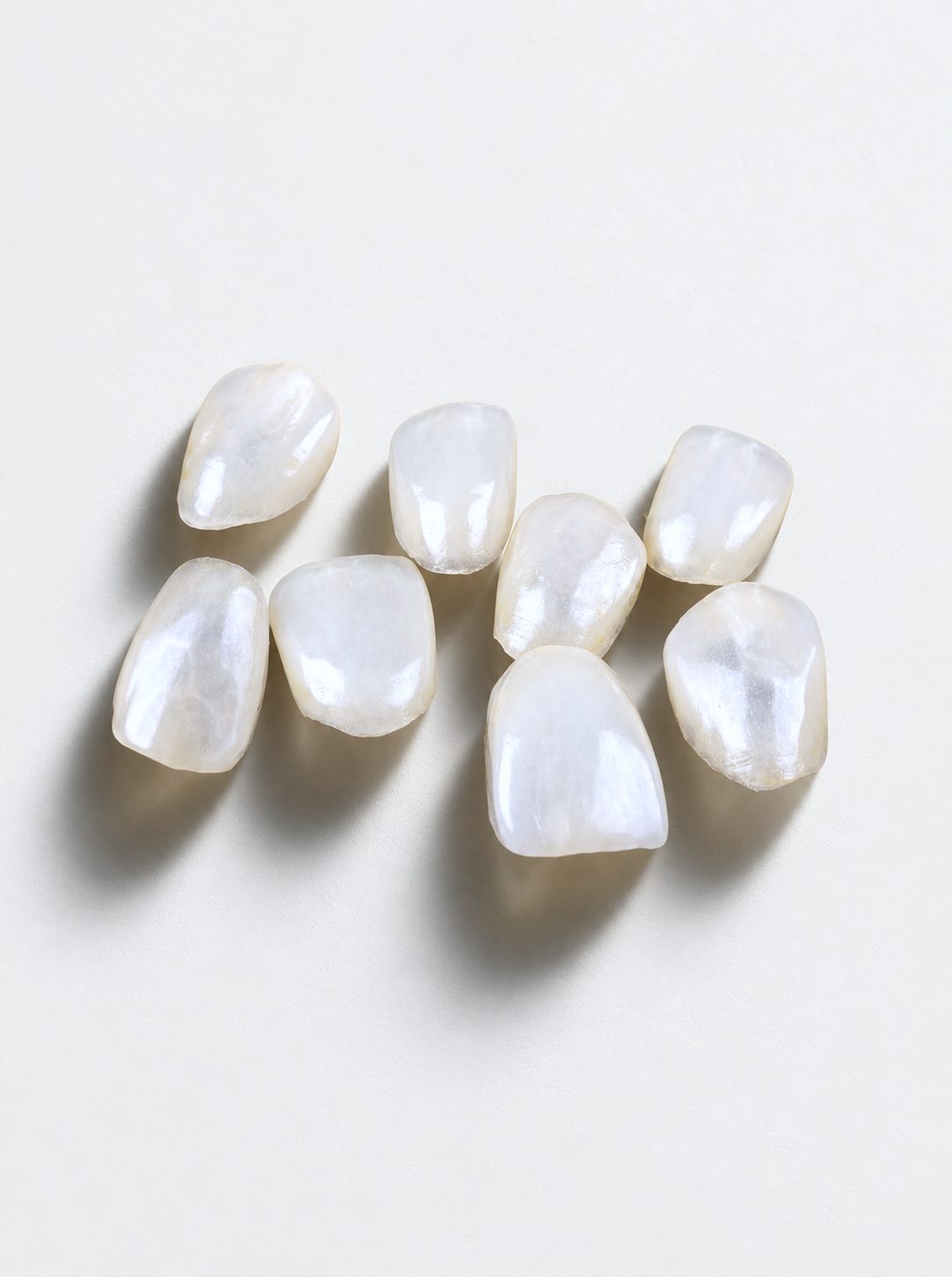 Handmade ceramic veneer held to the light, showing natural translucency